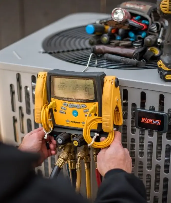 HVAC technician testing an outdoor air conditioner with a digital manifold gauge